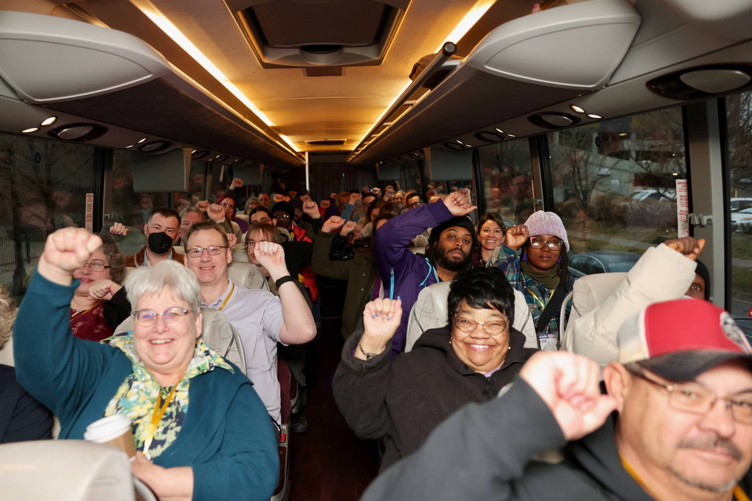 Bus passengers raising fists in unity and excitement.