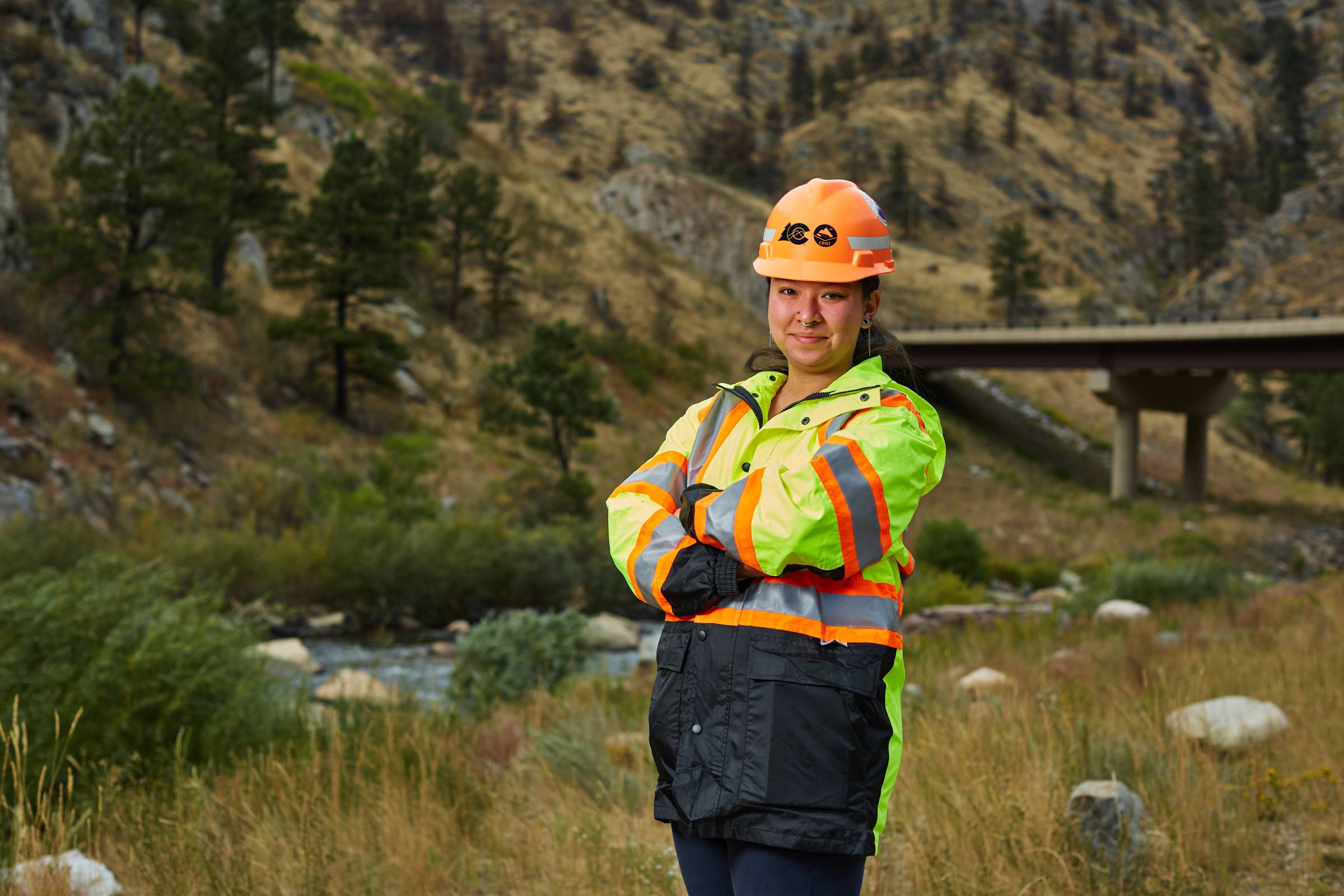Colorado Department of Transportation worker in safety gear near bridge site.